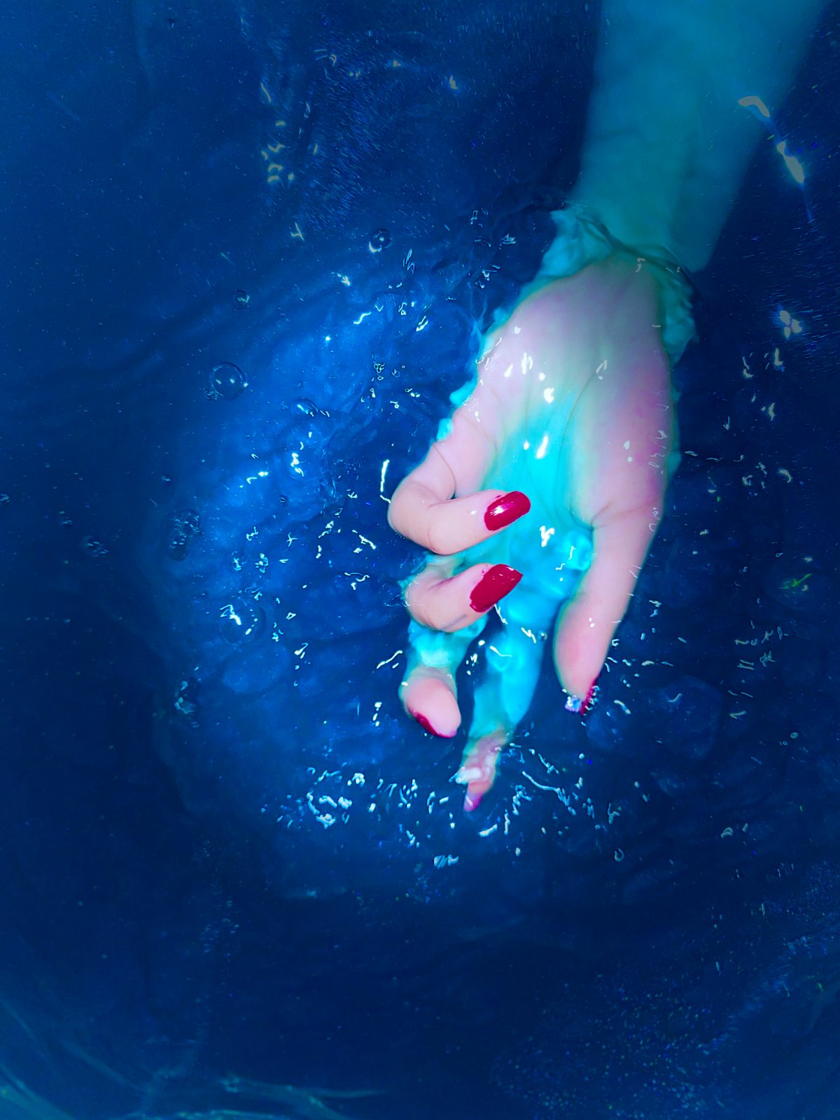 A hand resting in deep blue water